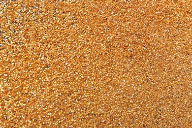 Photo of Texture of gold glitter as background, closeup