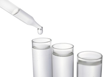 Photo of Dripping transparent liquid into test tube on white background, closeup