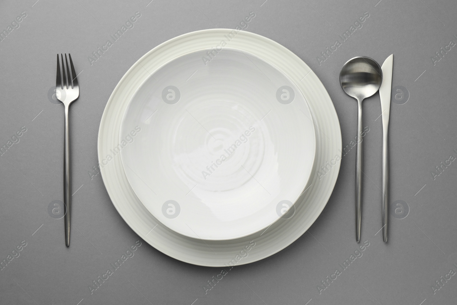 Photo of Clean dishes and cutlery on grey background, flat lay