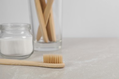 Photo of Bamboo toothbrushes and jar of baking soda on light marble table, space for text