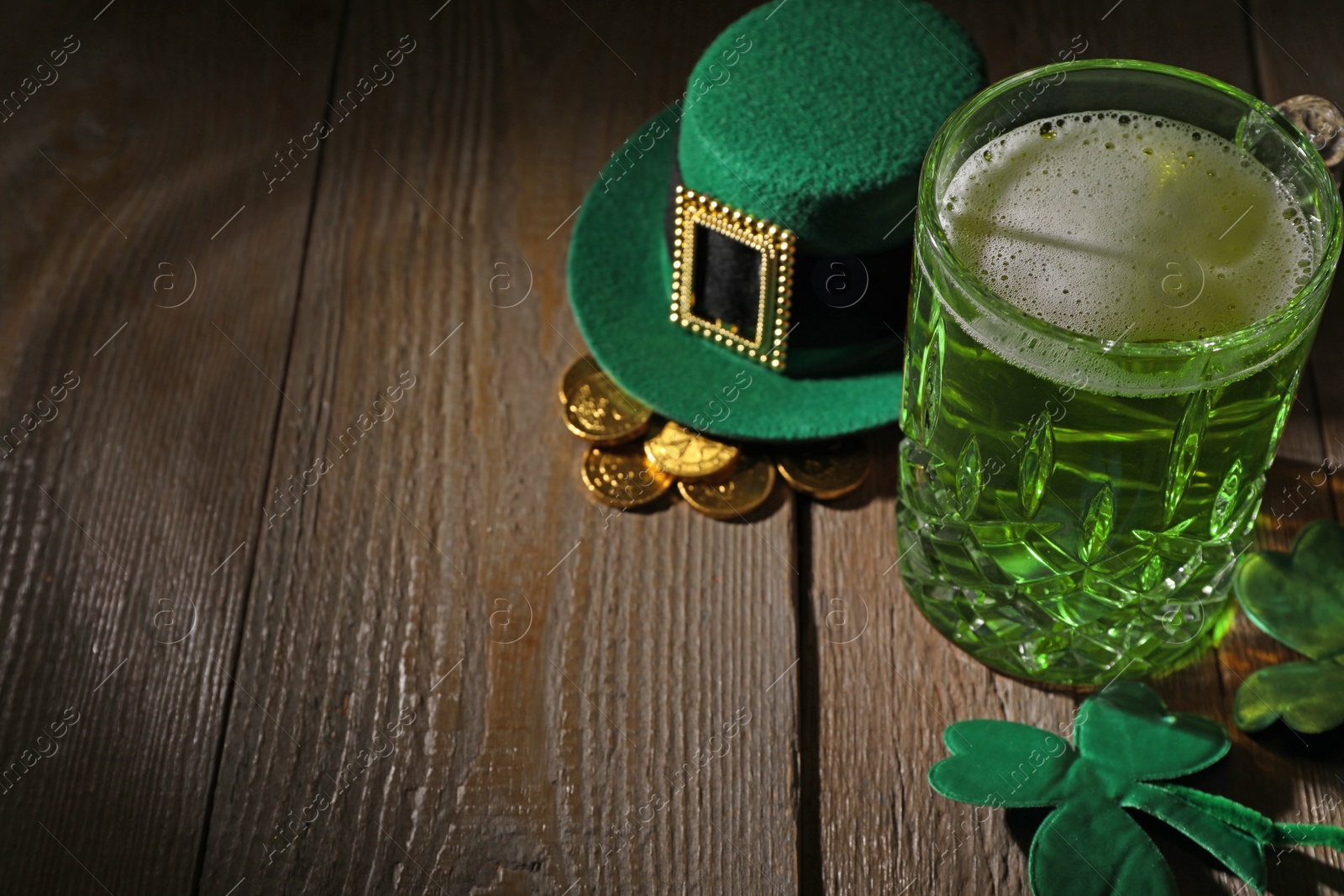 Photo of St. Patrick's day party. Green beer, leprechaun hat, gold and decorative clover leaves on wooden table. Space for text