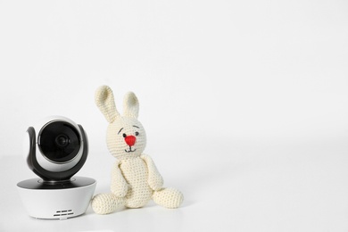 Photo of Baby camera with toy on table against white background, space for text. Video nanny