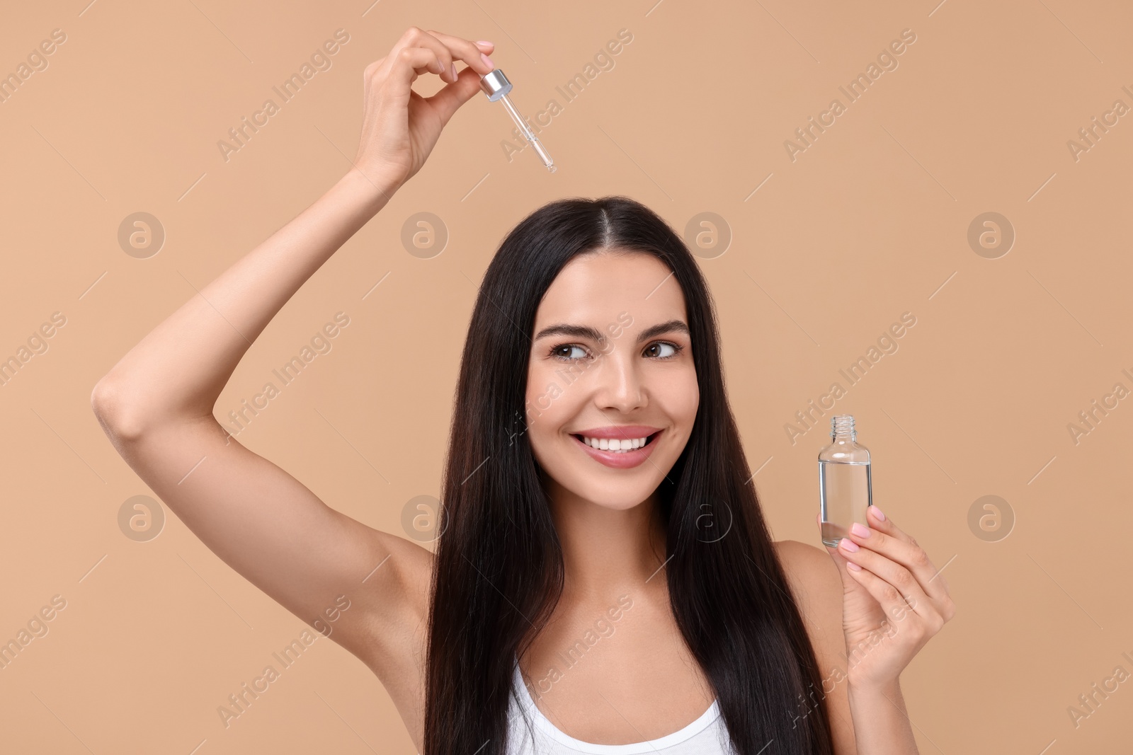 Photo of Beautiful woman applying hair serum on beige background. Cosmetic product