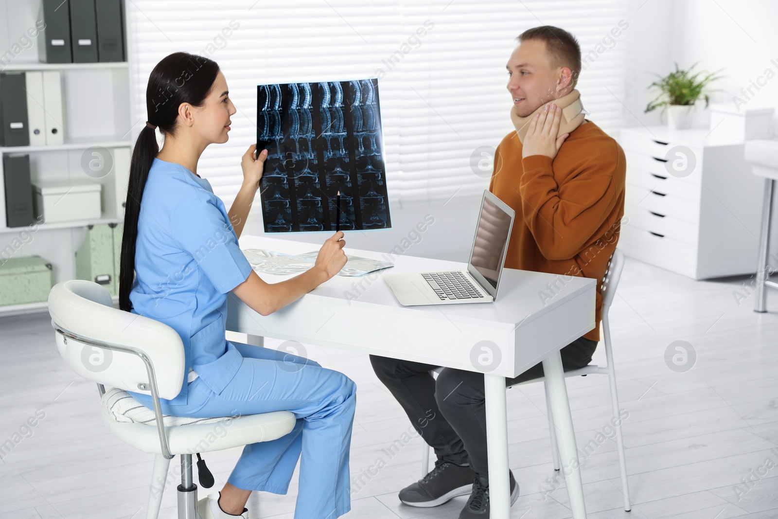 Photo of Doctor with neck MRI image consulting patient in clinic