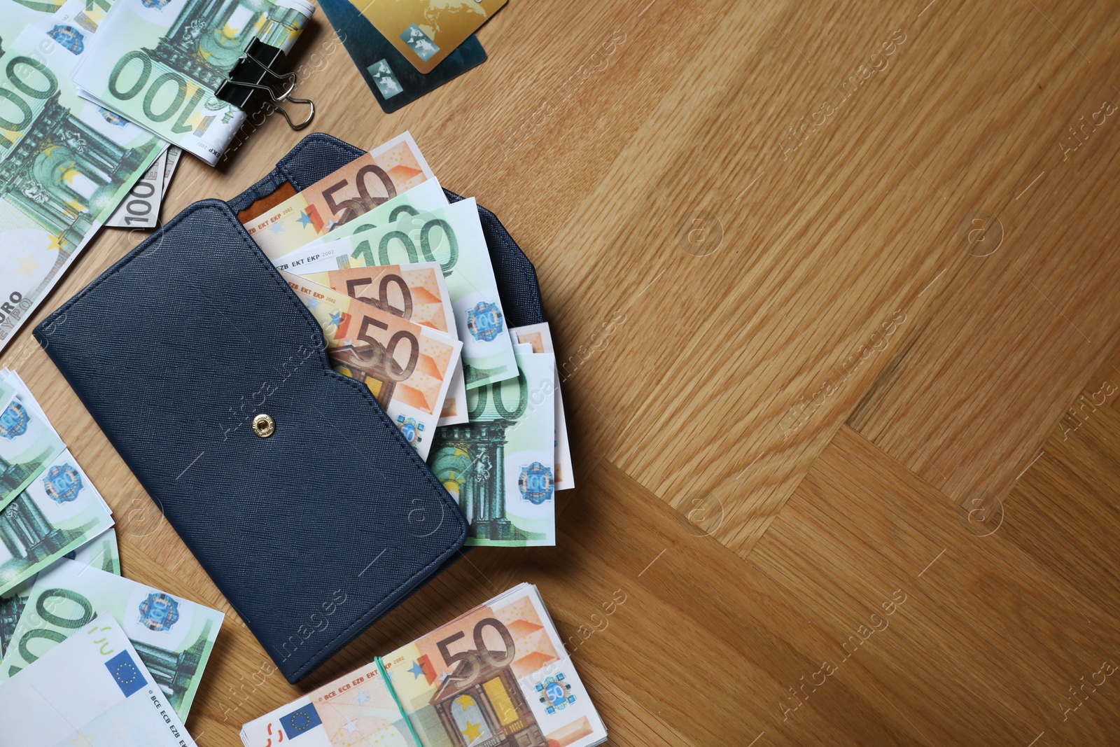 Photo of Wallet, different Euro banknotes and credit cards on wooden table, flat lay with space for text. Money exchange