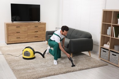 Photo of Dry cleaner's employee hoovering carpet with vacuum cleaner in room