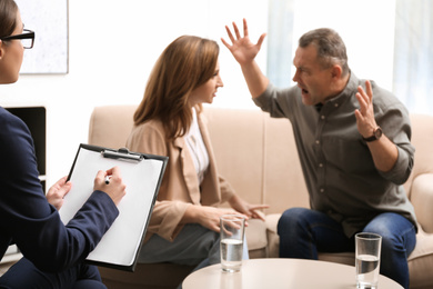 Photo of Psychotherapist working with couple in office. Family counselling