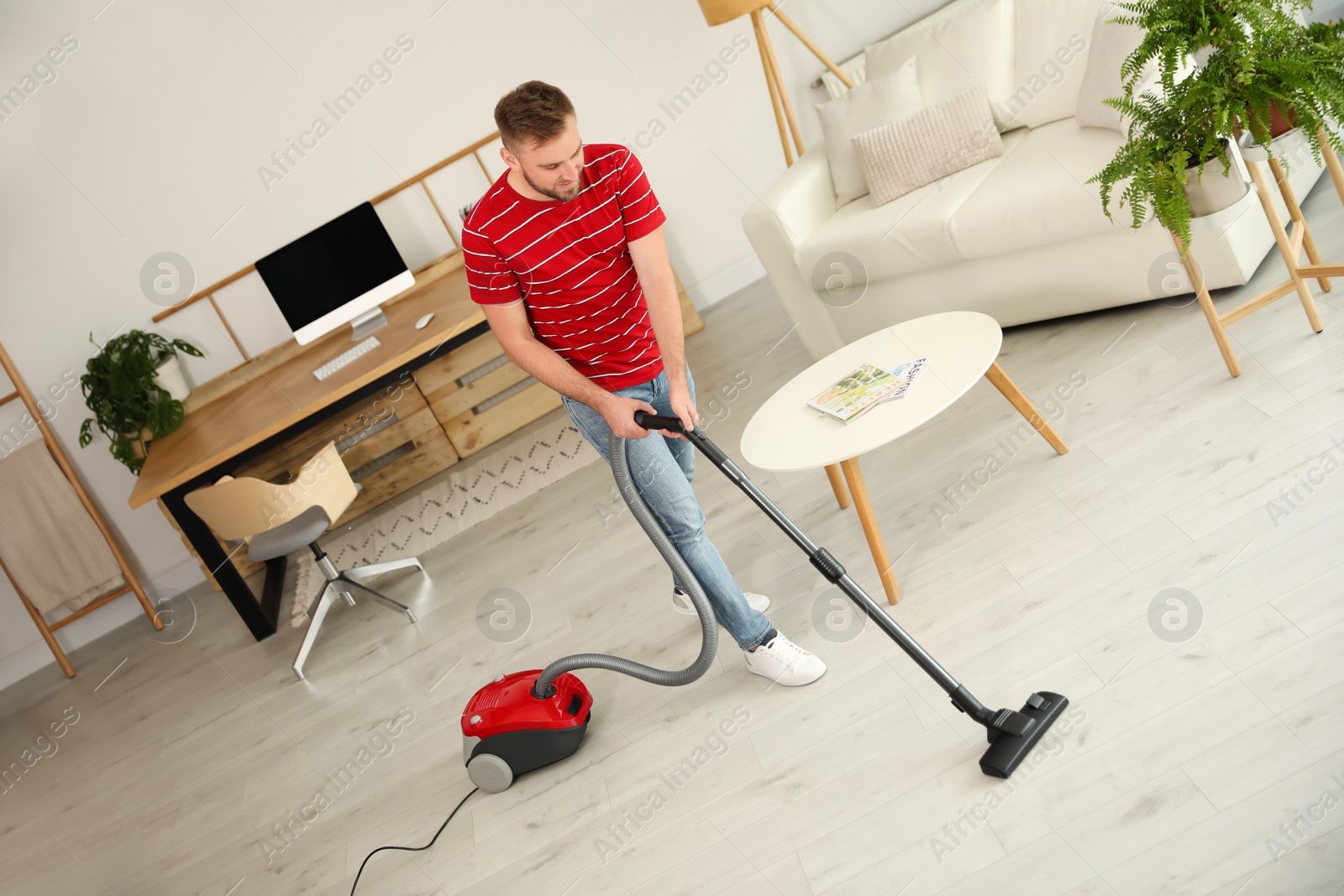 Photo of Young man using vacuum cleaner at home