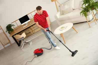 Young man using vacuum cleaner at home