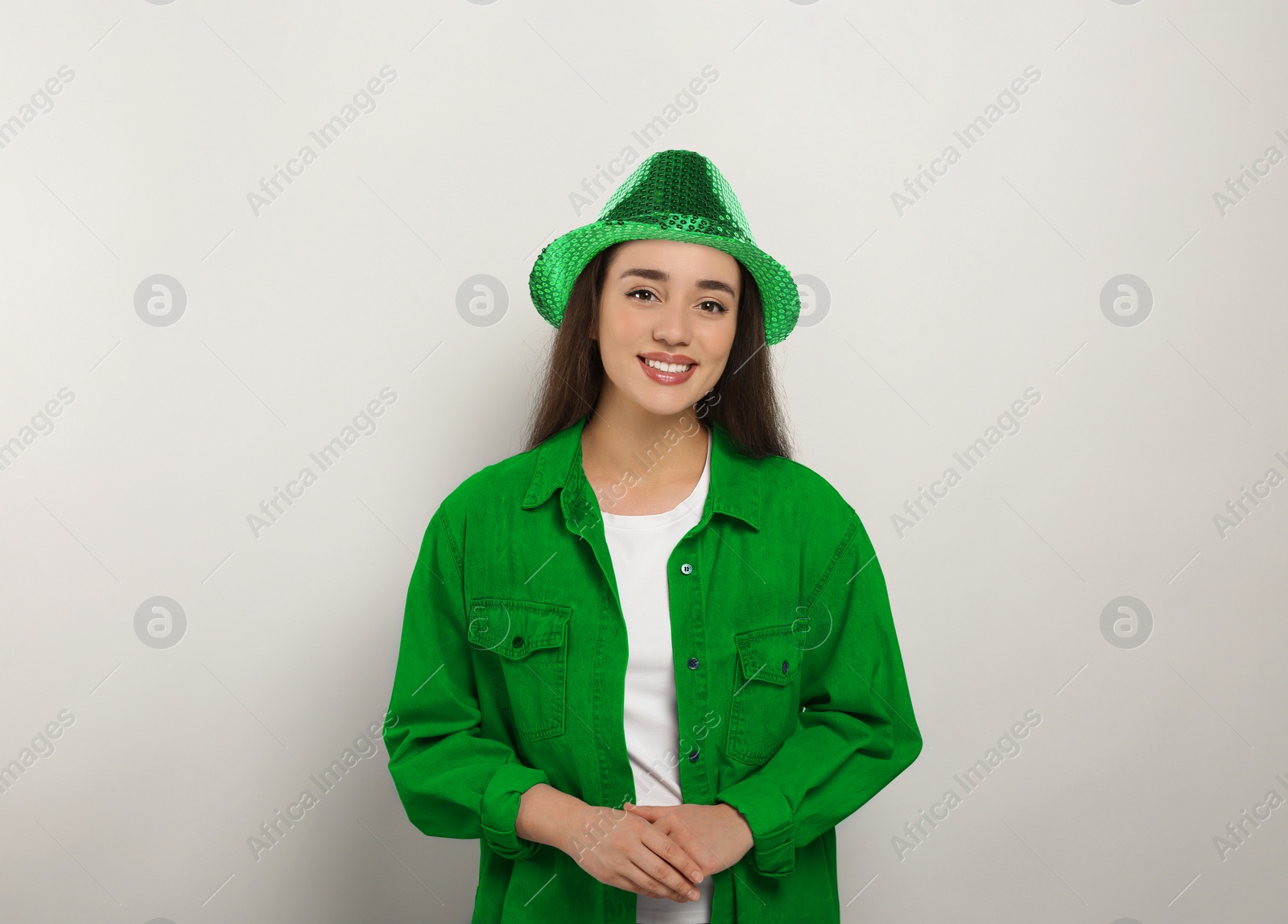 Image of St. Patrick's day party. Pretty woman in green leprechaun hat on light grey background