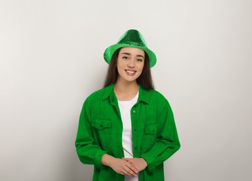 St. Patrick's day party. Pretty woman in green leprechaun hat on light grey background