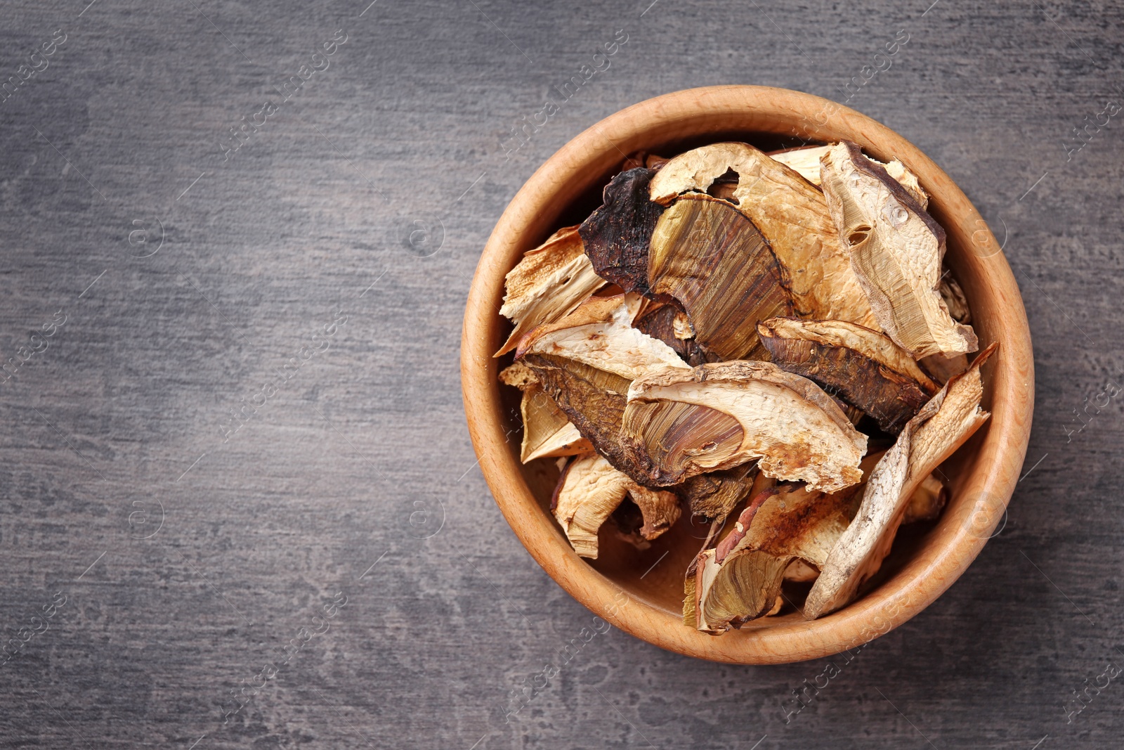 Photo of Bowl of dried mushrooms on color background, top view. Space for text