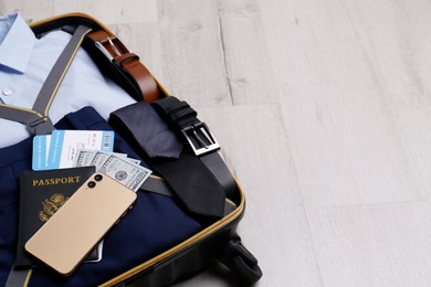 Photo of Packed suitcase with business trip stuff on wooden surface. Space for text