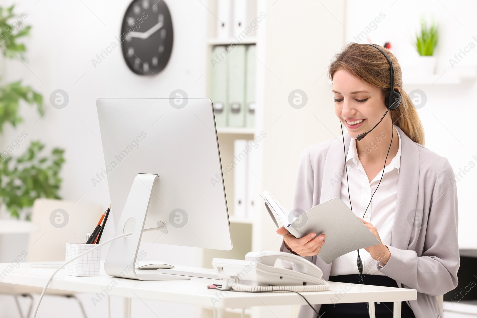 Photo of Female receptionist with headset at desk in office