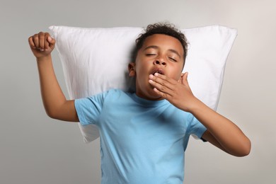 Photo of Boy with pillow yawning on grey background. Insomnia problem