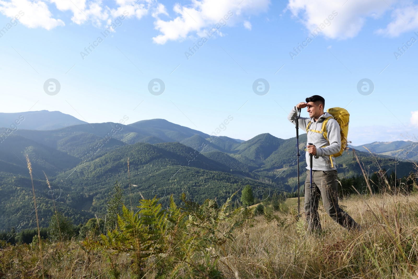 Photo of Tourist with backpack and trekking poles enjoying mountain landscape, space for text