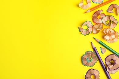 Photo of Pencils and shavings on yellow background, flat lay. Space for text