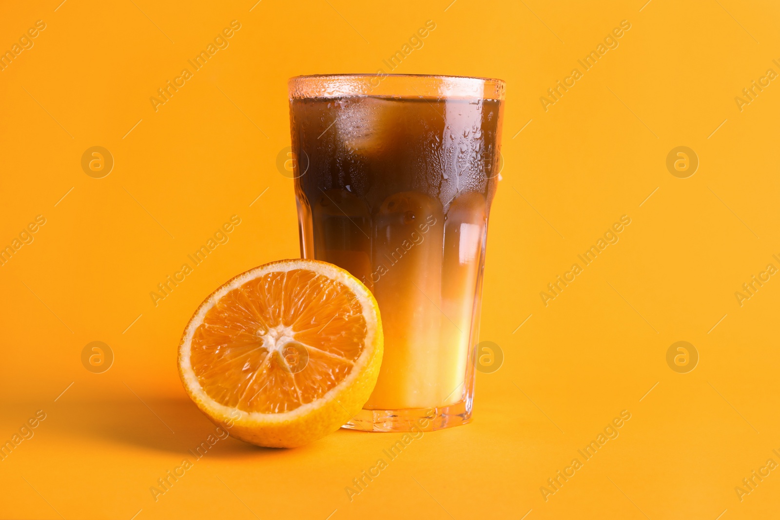 Photo of Tasty refreshing drink with coffee and orange juice on bright color background