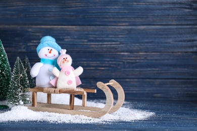 Photo of Sleigh with decorative snowmen on blue wooden background, space for text