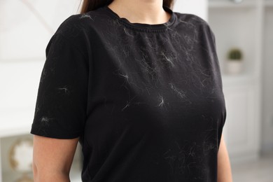 Photo of Woman with pet hair on her black clothers indoors, closeup