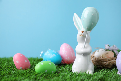 Easter bunny and painted eggs on green grass, space for text