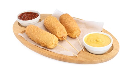 Delicious deep fried corn dogs with board and sauces isolated on white