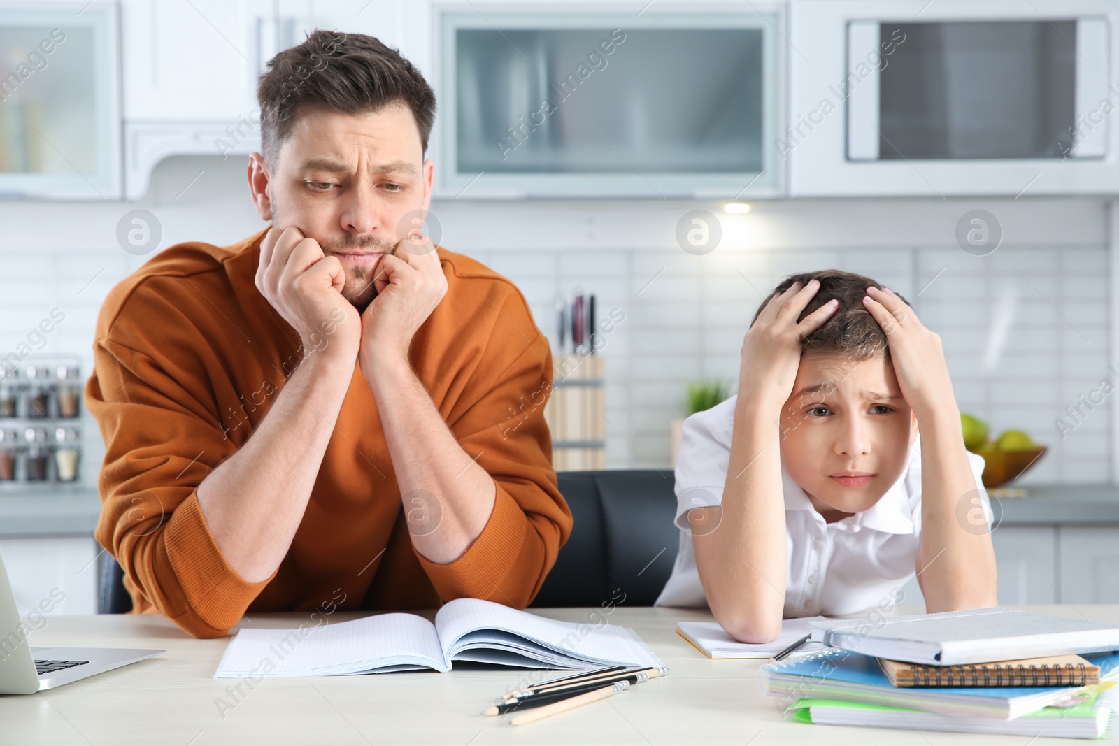 Photo of Dad helping his son with difficult homework assignment in kitchen