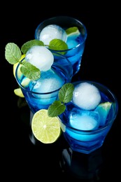 Photo of Delicious cocktails with ice balls, mint and lime on black background