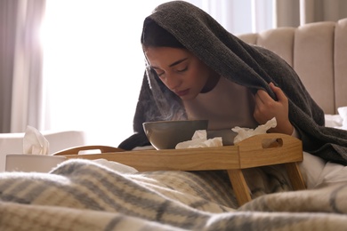 Photo of Woman with plaid doing inhalation above bowl on bed