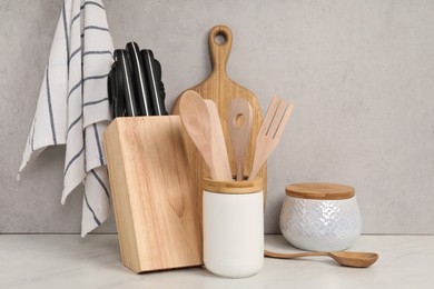 Set of different kitchen utensils on white near gray wall