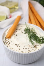 Delicious cream cheese with grissini stick and dill on white tiled table, closeup