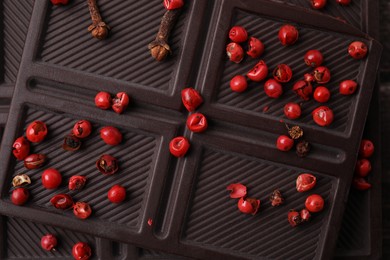 Photo of Texture of delicious chocolate bar with red peppercorns as background, top view