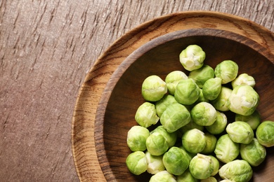 Bowl with fresh Brussels sprouts on wooden table, top view. Space for text