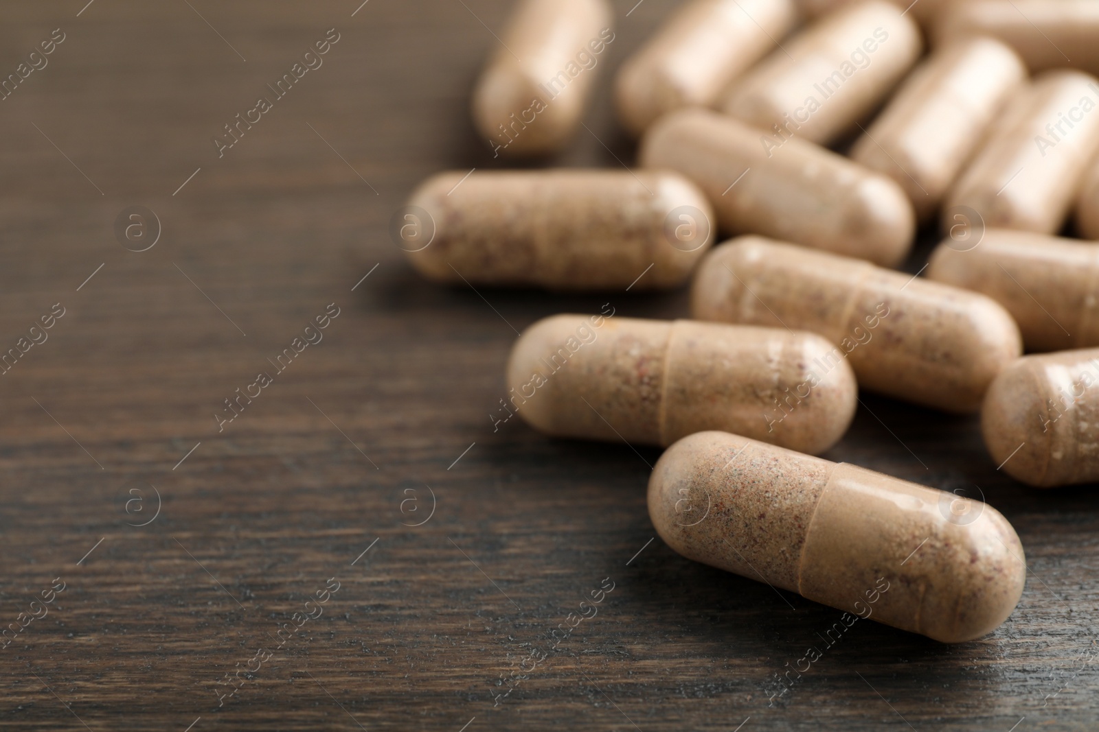 Photo of Gelatin capsules on wooden table, closeup. Space for text