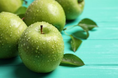 Photo of Fresh ripe green apples with water drops on turquoise wooden table, closeup
