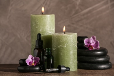 Photo of Composition with candles and spa stones on wooden table
