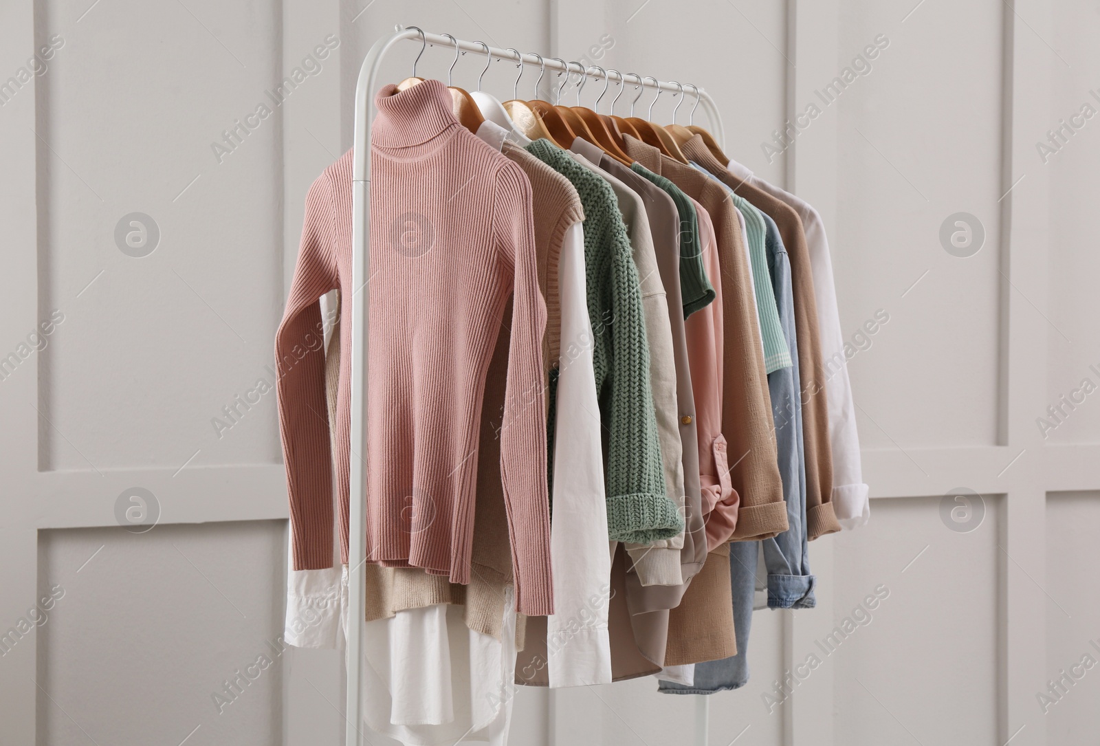 Photo of Rack with stylish women's clothes near light wall