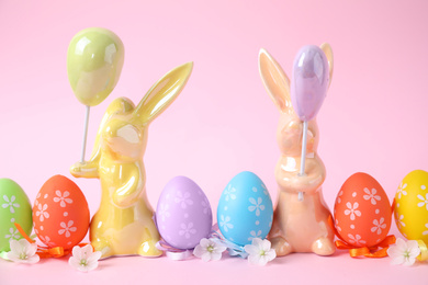 Easter bunnies and painted eggs on pink background