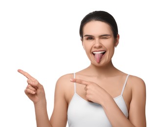 Photo of Happy young woman showing her tongue and pointing on white background