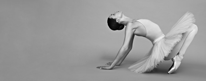 Young ballerina practicing dance moves on light grey background. Black and white effect. Banner design with space for text