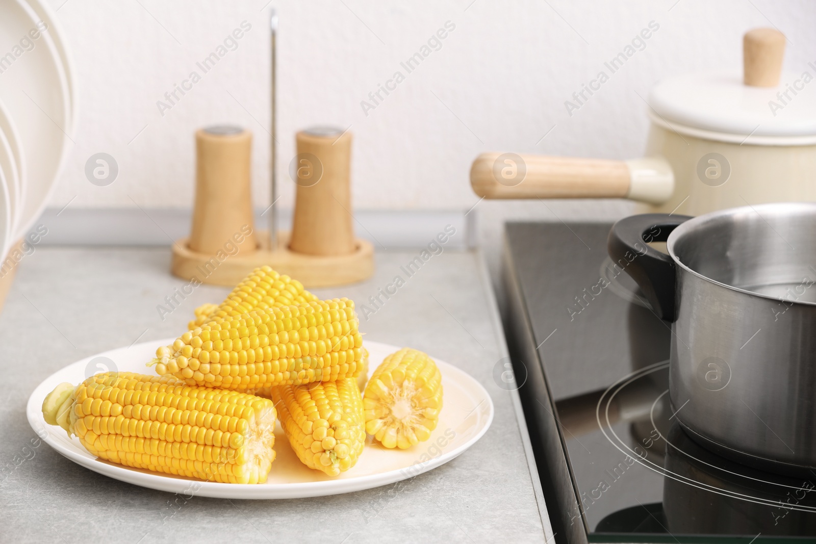 Photo of Plate with ripe corn cobs on kitchen table