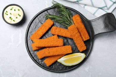 Photo of Fresh breaded fish fingers, sauce and lemon served on light grey table, flat lay