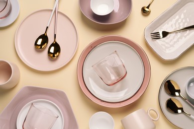 Photo of Different dishware and cutlery on beige background, flat lay