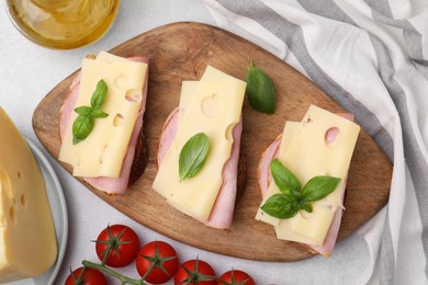 Delicious sandwiches with ham, cheese and products on light table, flat lay
