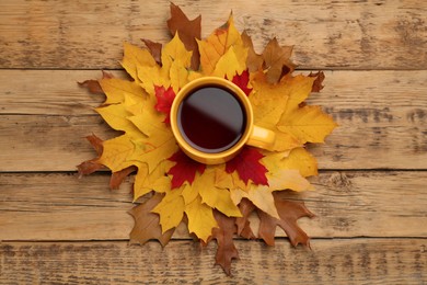 Photo of Cup of hot tea and autumn leaves on wooden table, flat lay