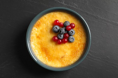 Delicious creme brulee with fresh berries on black table, top view