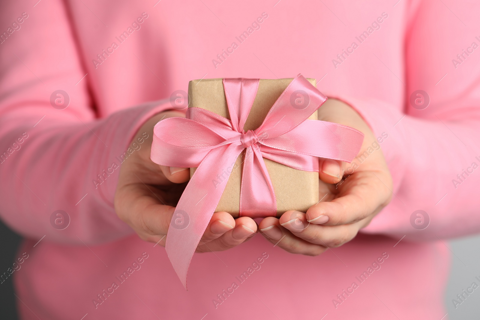 Photo of Woman holding gift box with pink bow, closeup