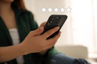 Image of Woman leaving review online via smartphone, closeup. Five stars over gadget