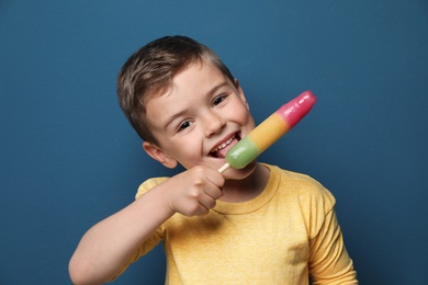 Adorable little boy with delicious ice cream against color background