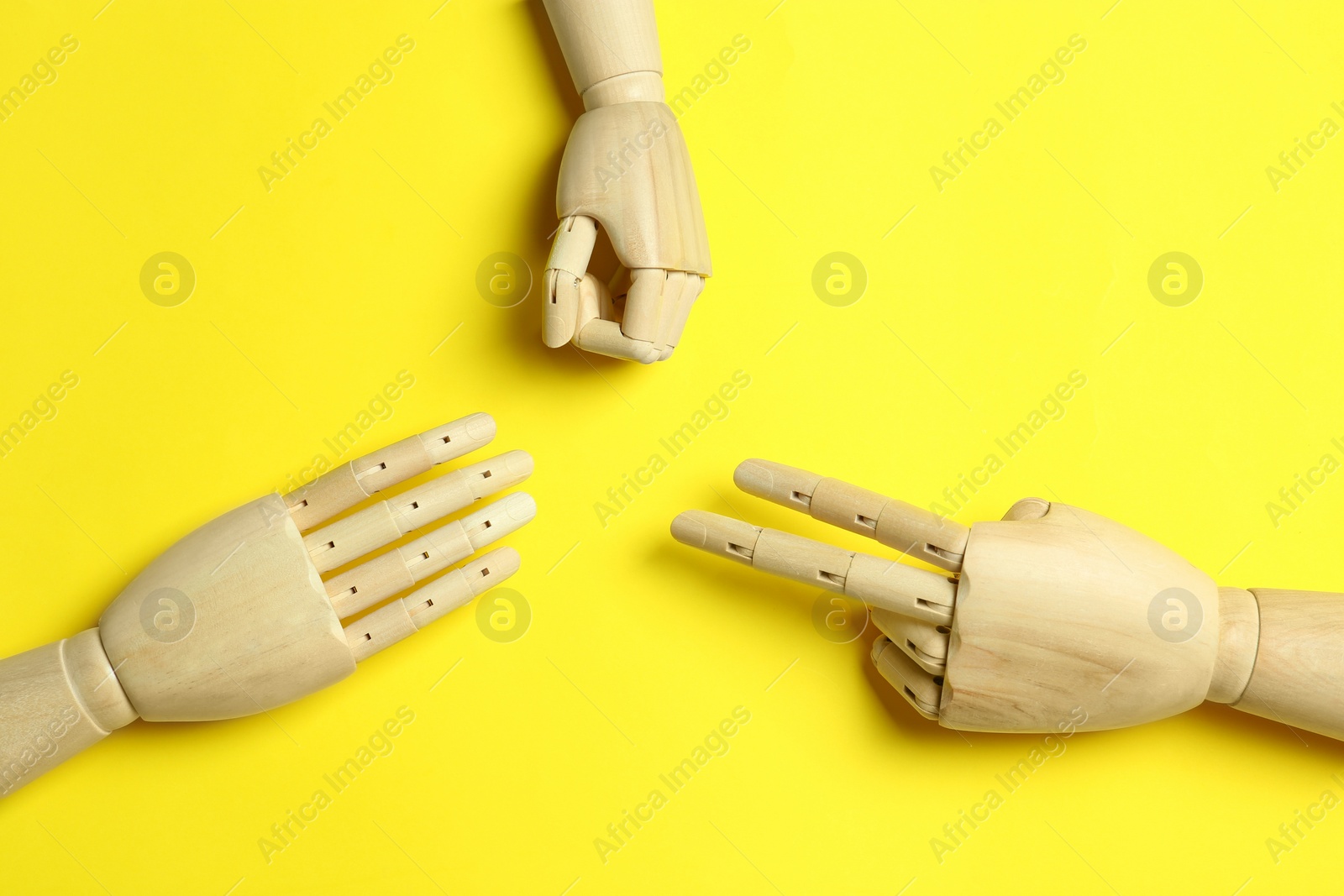 Photo of Wooden mannequin hands on yellow background, flat lay